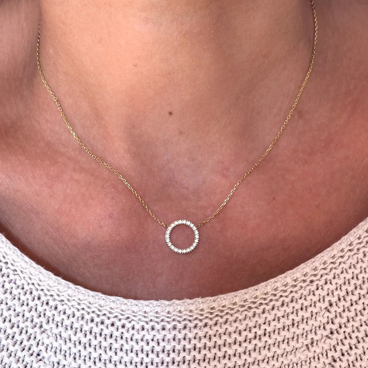 Collier doré à chaîne fine et cercle ajouré serti d’oxydes de zirconium, porté au décolleté