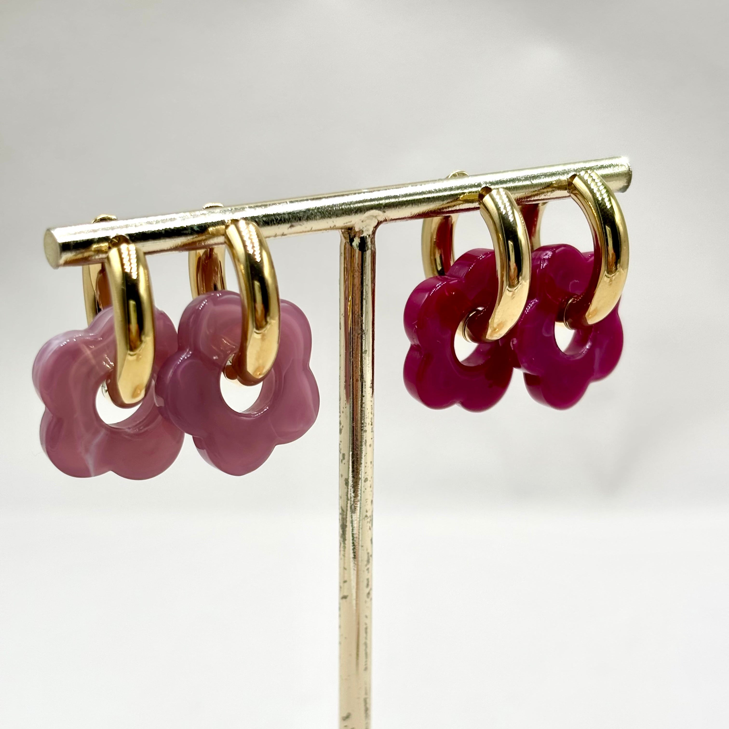Boucles d'oreilles créoles en acier doré orné d'une fleur en acétate violet et prune sur présentoir