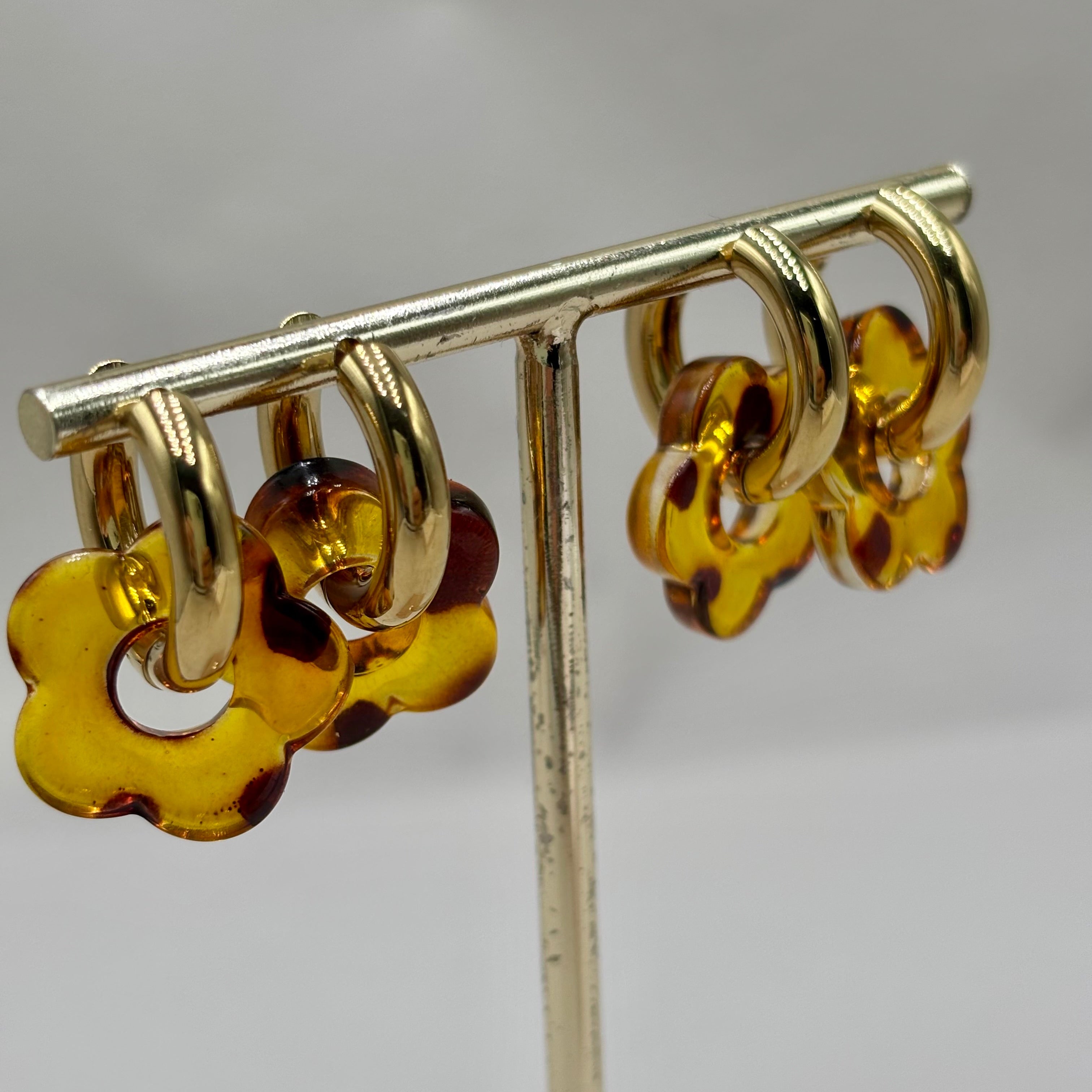 Boucles d'oreilles créoles en acier doré orné d'une fleur en acétate léopard sur présentoir
