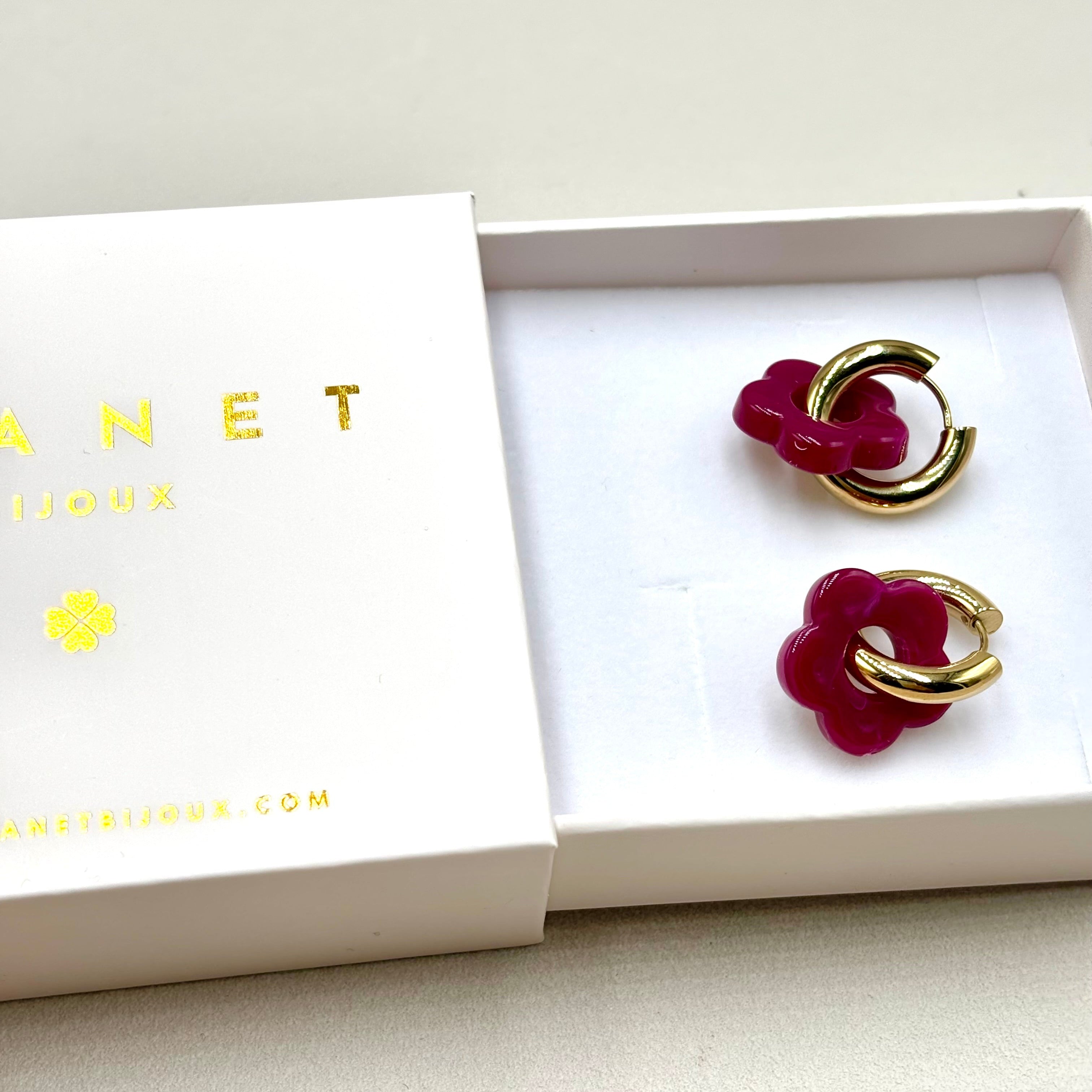 Boucles d'oreilles créoles en acier doré orné d'une fleur en acétate prune dans une boite cadeau Djanet Bijoux