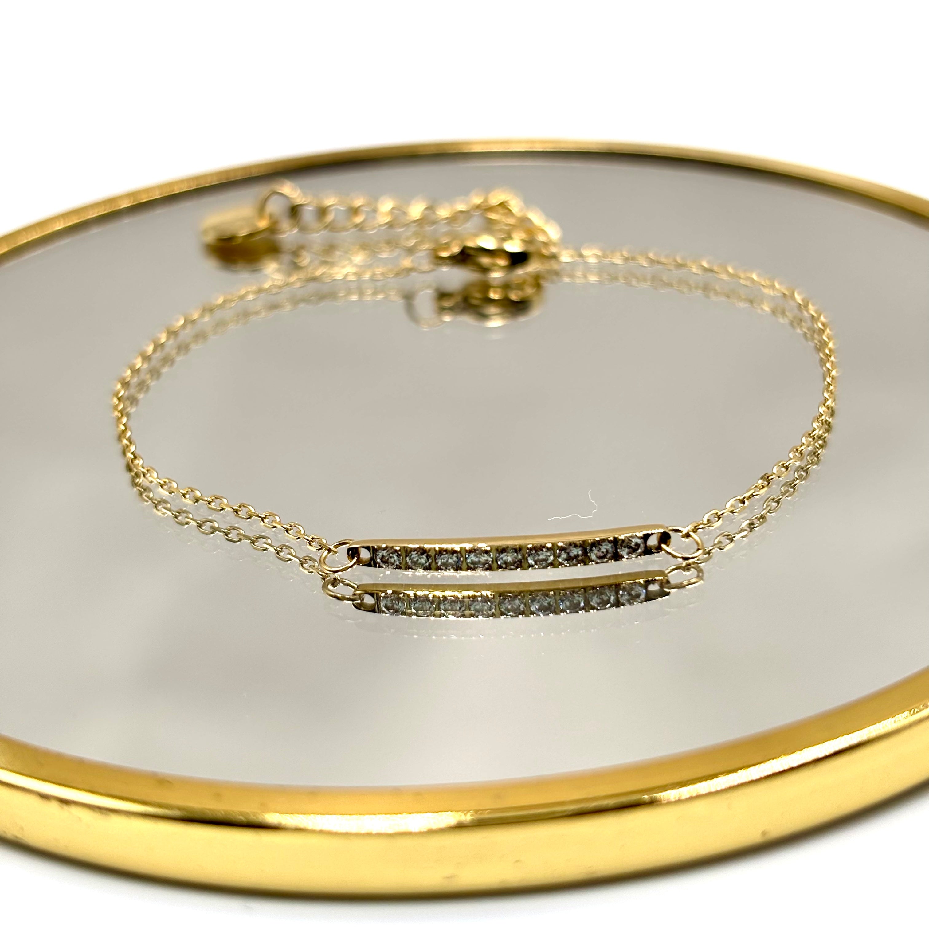 Bracelet chaine Carlota en acier inoxydable orné d'une barre serties d'oxyde de zirconium présenté sur un miroir contour cuivre