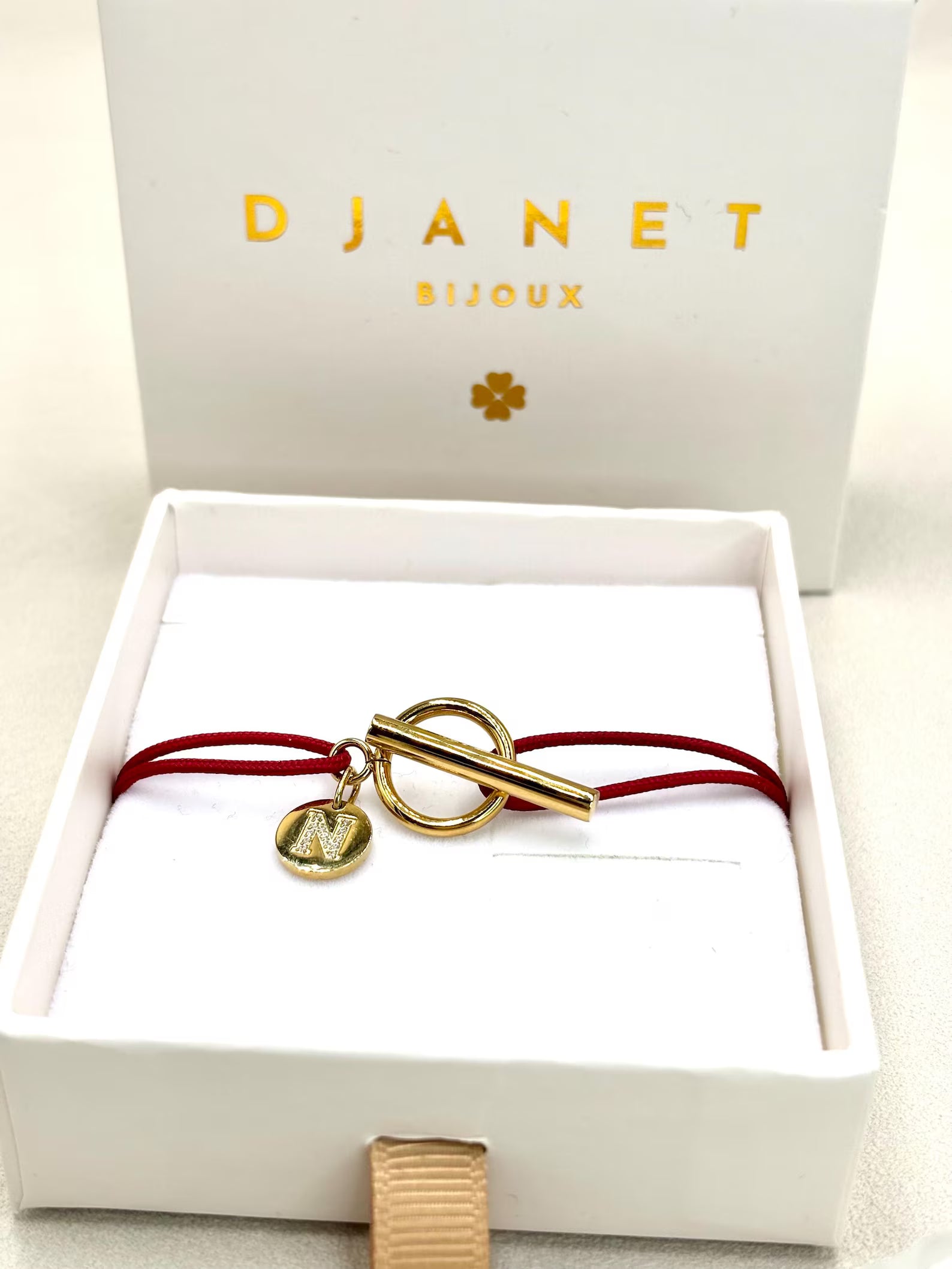 Bracelet cordon rouge fermoir T Toggle et charm lettre zirconium gravée présenté sur boite cadeau Djanet
