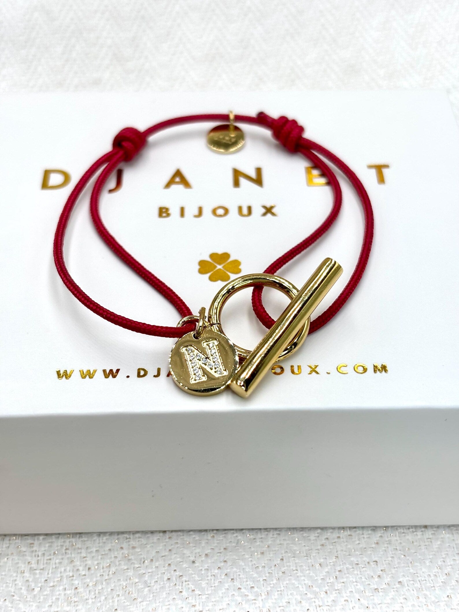 Bracelet cordon rouge fermoir avec charm lettre zirconium gravée présenté sur boite cadeau Djanet