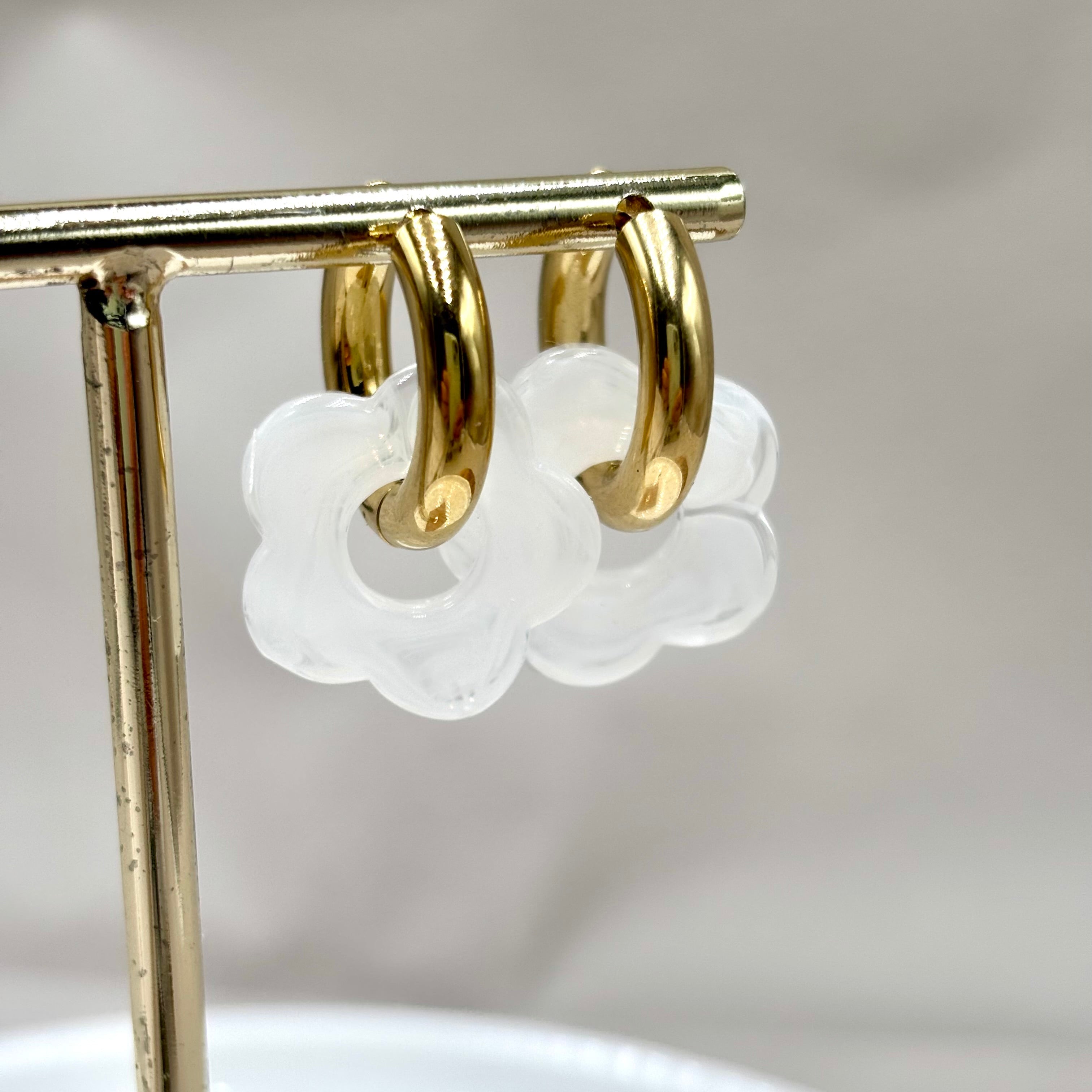 Boucles d'oreilles créoles en acier doré orné d'une fleur en acétate blanc