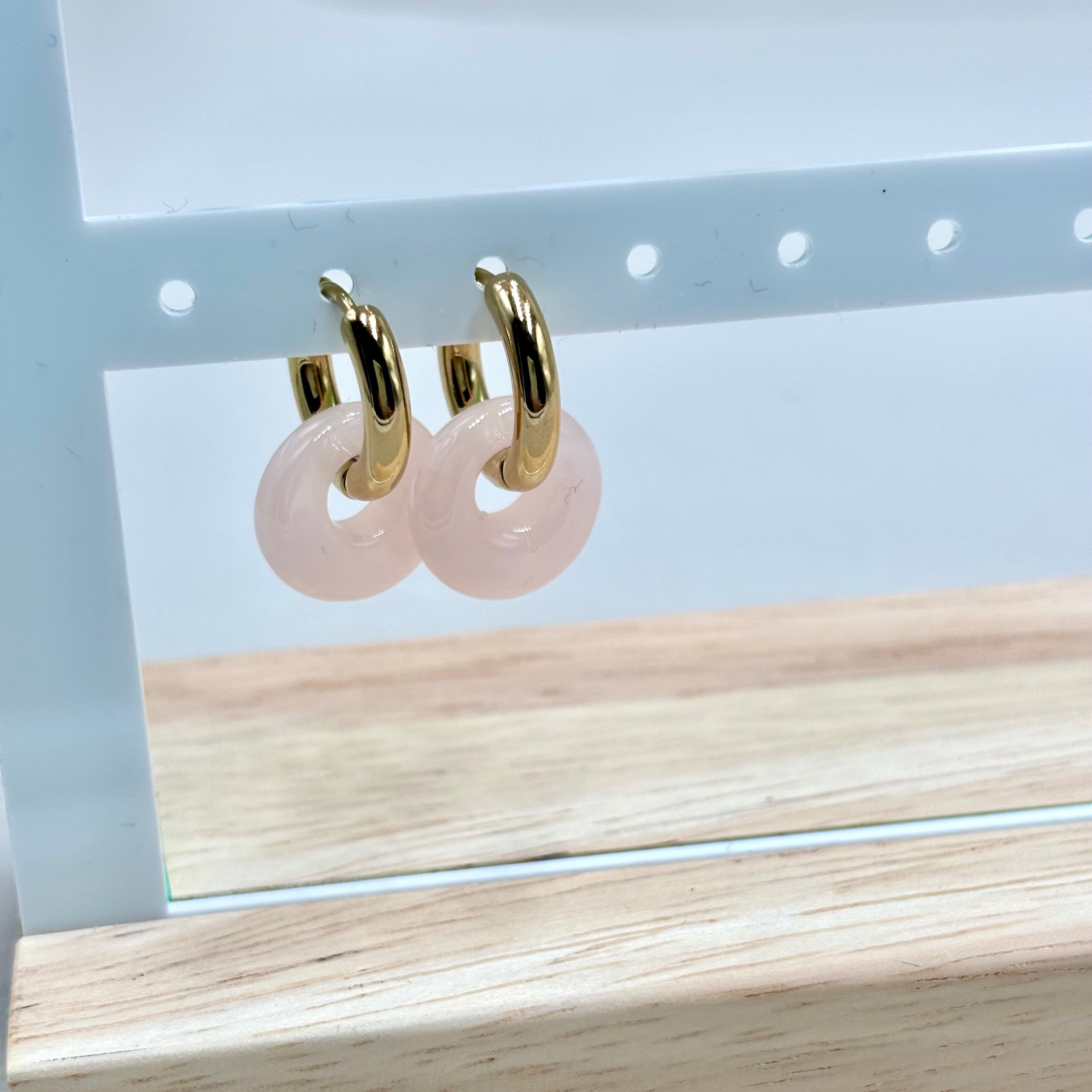 Boucles d'oreilles mini créoles en acier inoxydable doré en acétate rose sur présentoir rose