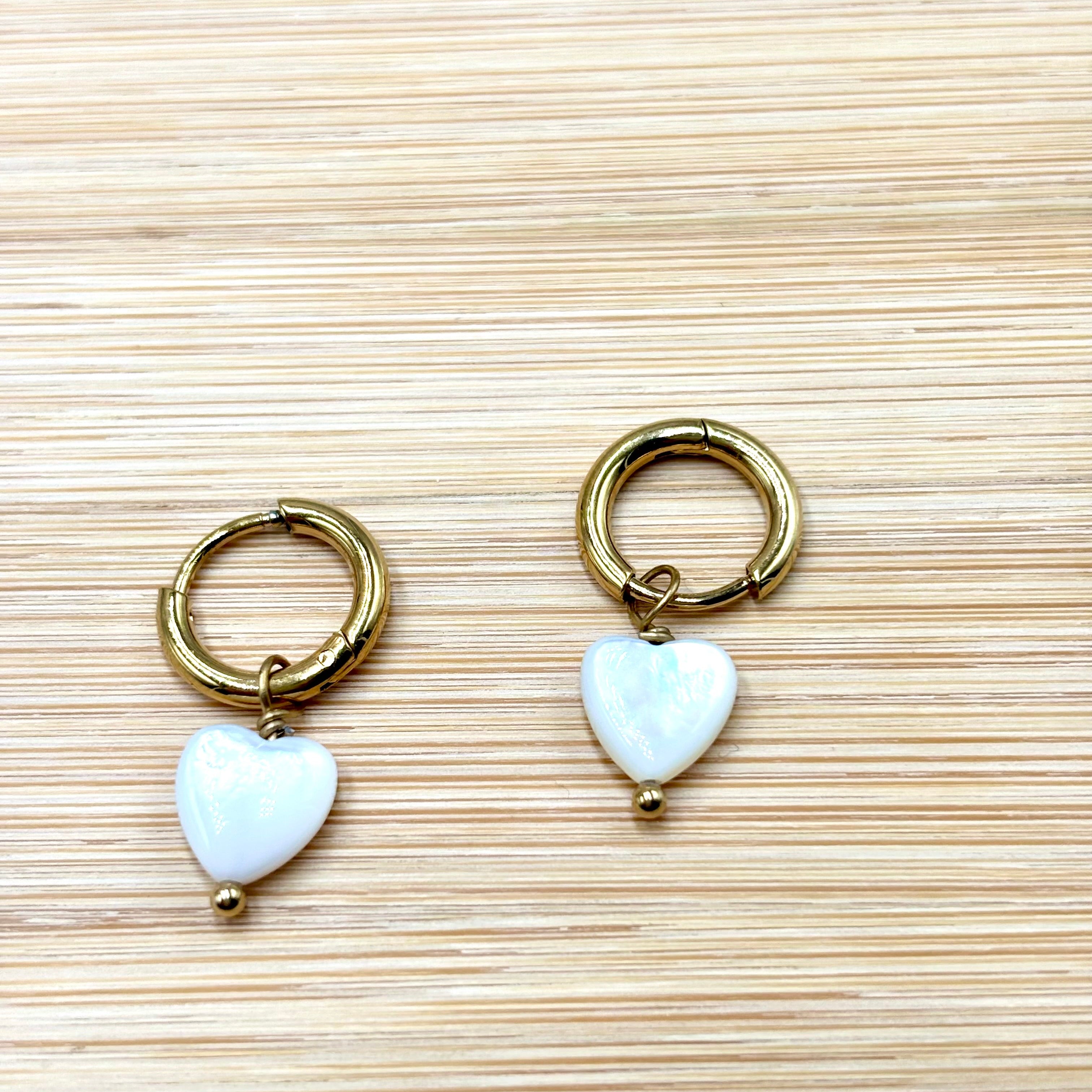 Boucles d'oreilles mini créoles en acier inoxydable doré et coeur nacré fond bois Djanet Bijoux
