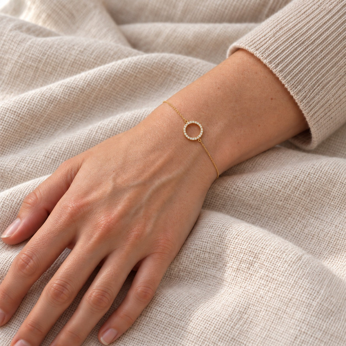 Gold-tone stainless steel bracelet with a cubic zirconia circle, worn on the wrist.