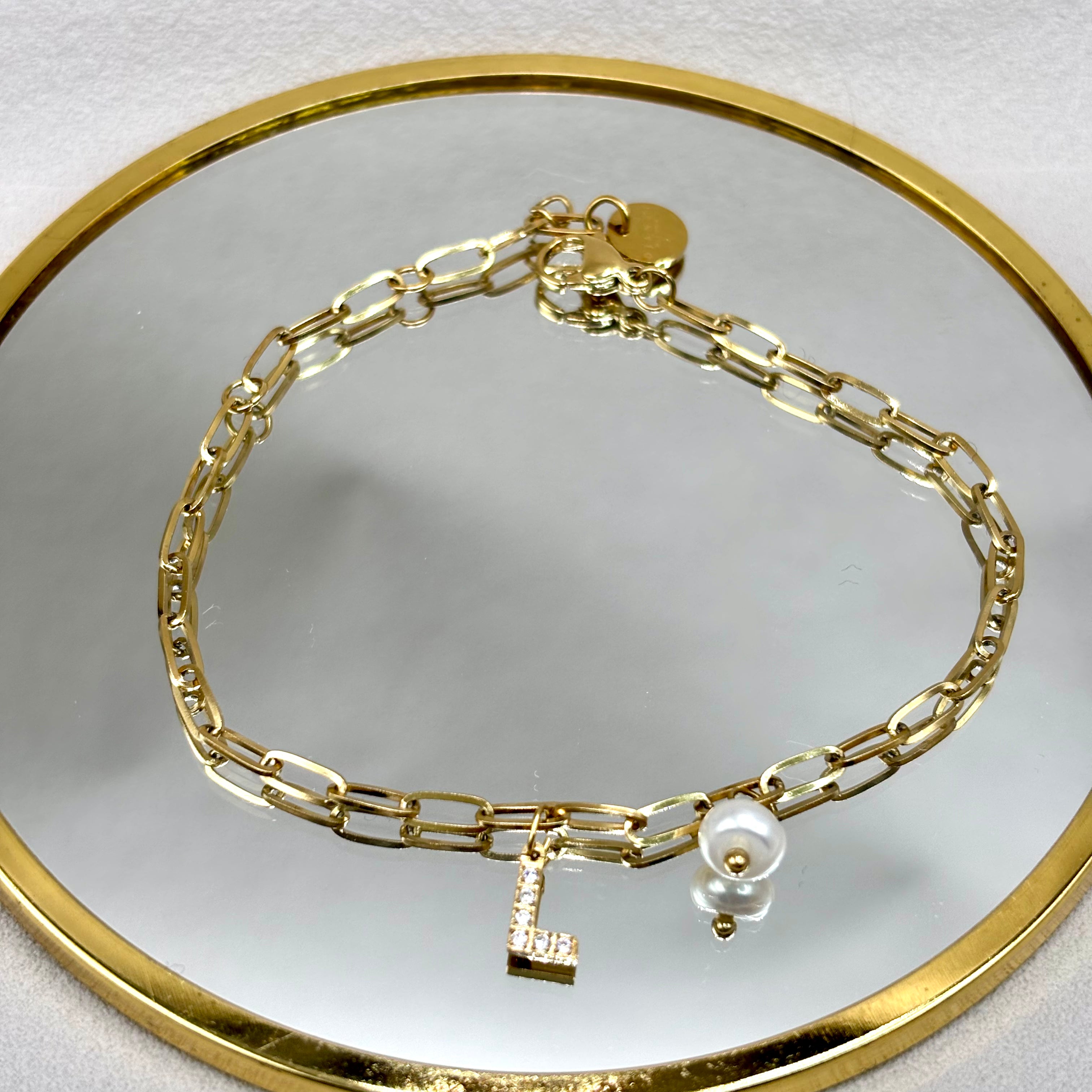 Bracelet personnalise maille ovale en acier doré avec breloques perle et initiale zirconium sur miroir 