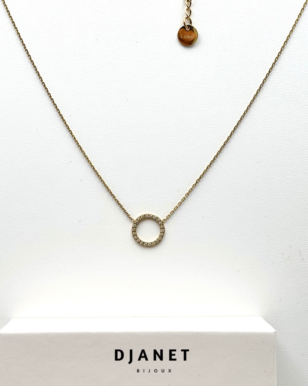 Collier Aura composé d'une chaine fine acier doré 14K orné d'un cercle ajouré serti d'oxydes de  zirconium sur fond blanc 