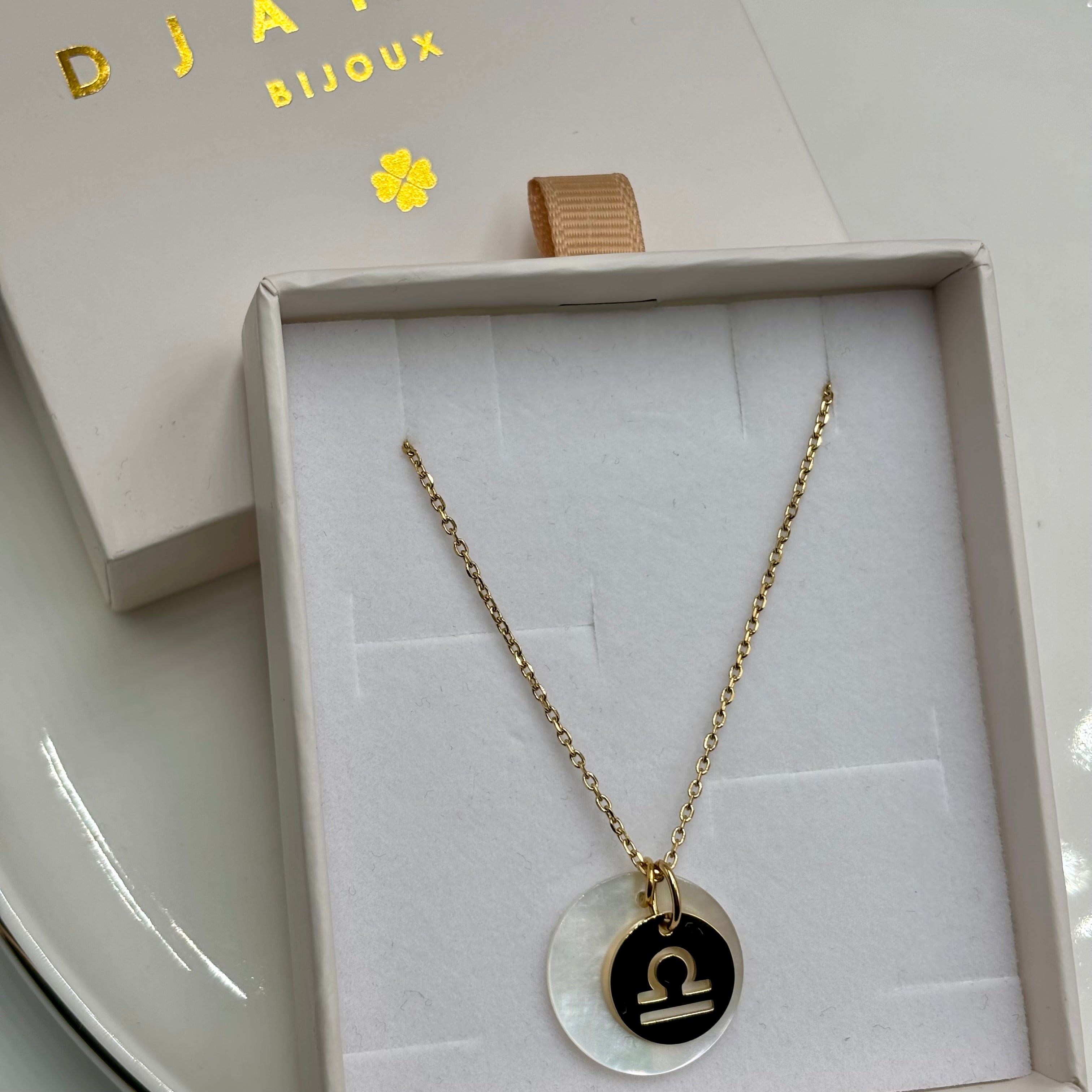 Collier personnalise signe Astro balance sur chaine maille forçat acier dore et medaille ronde en nacre présenté sur boite cadeau Djanet Bijoux