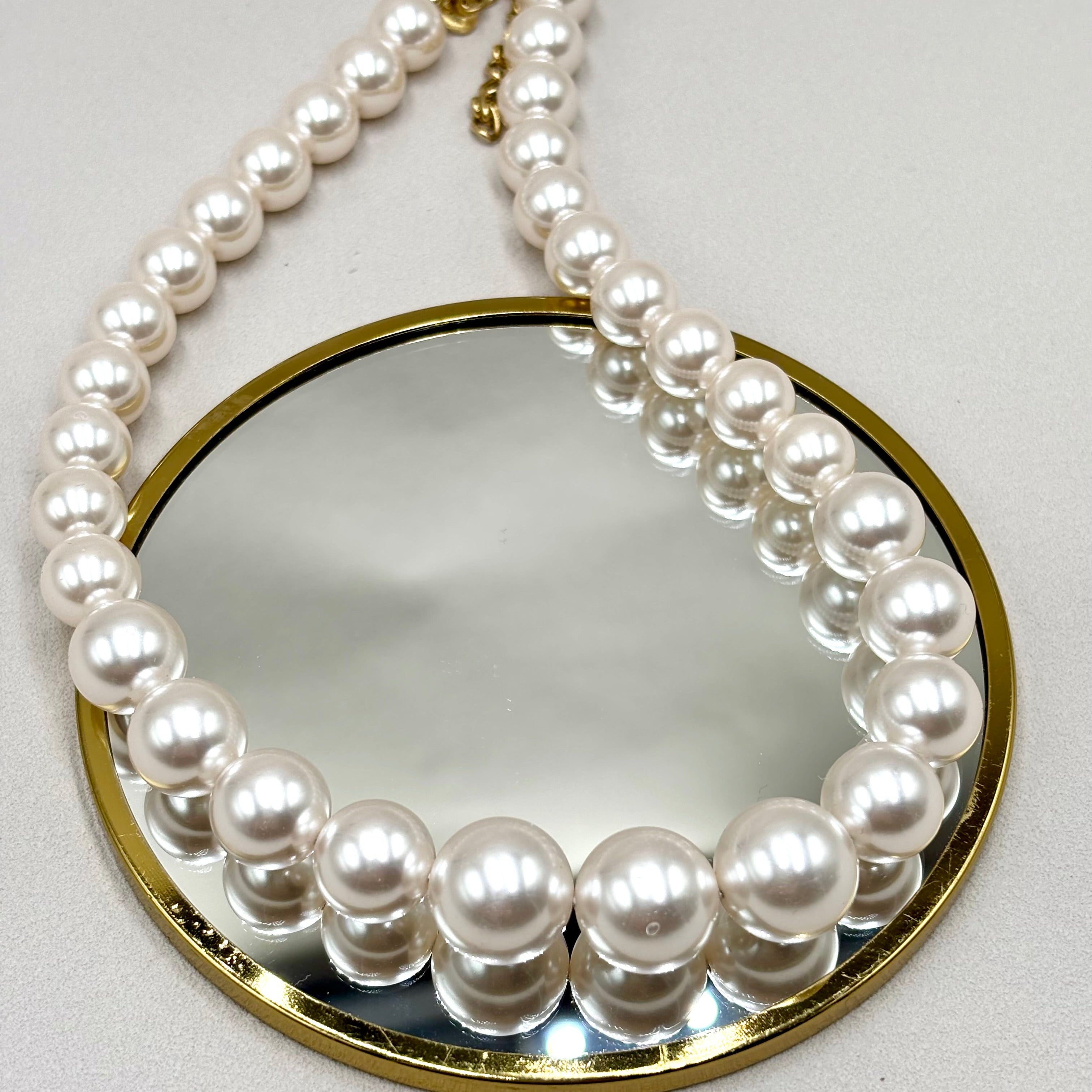 Collier grosses perles rondes et lisses en résine blanche présenté sur miroir