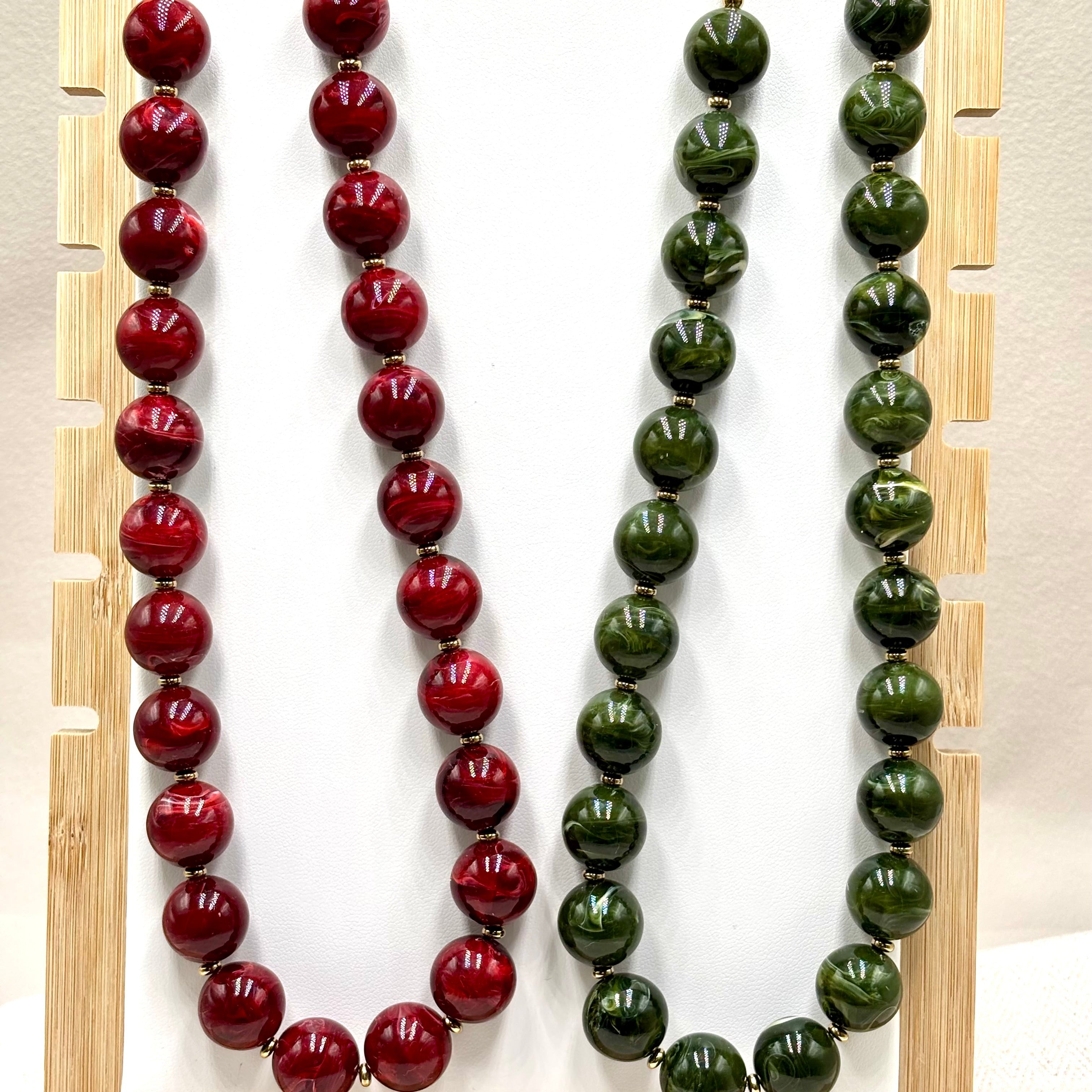 Colliers grosses boules en résine vert et rouge cerise et acier doré Perla Djanet Bijoux sur présentoirs