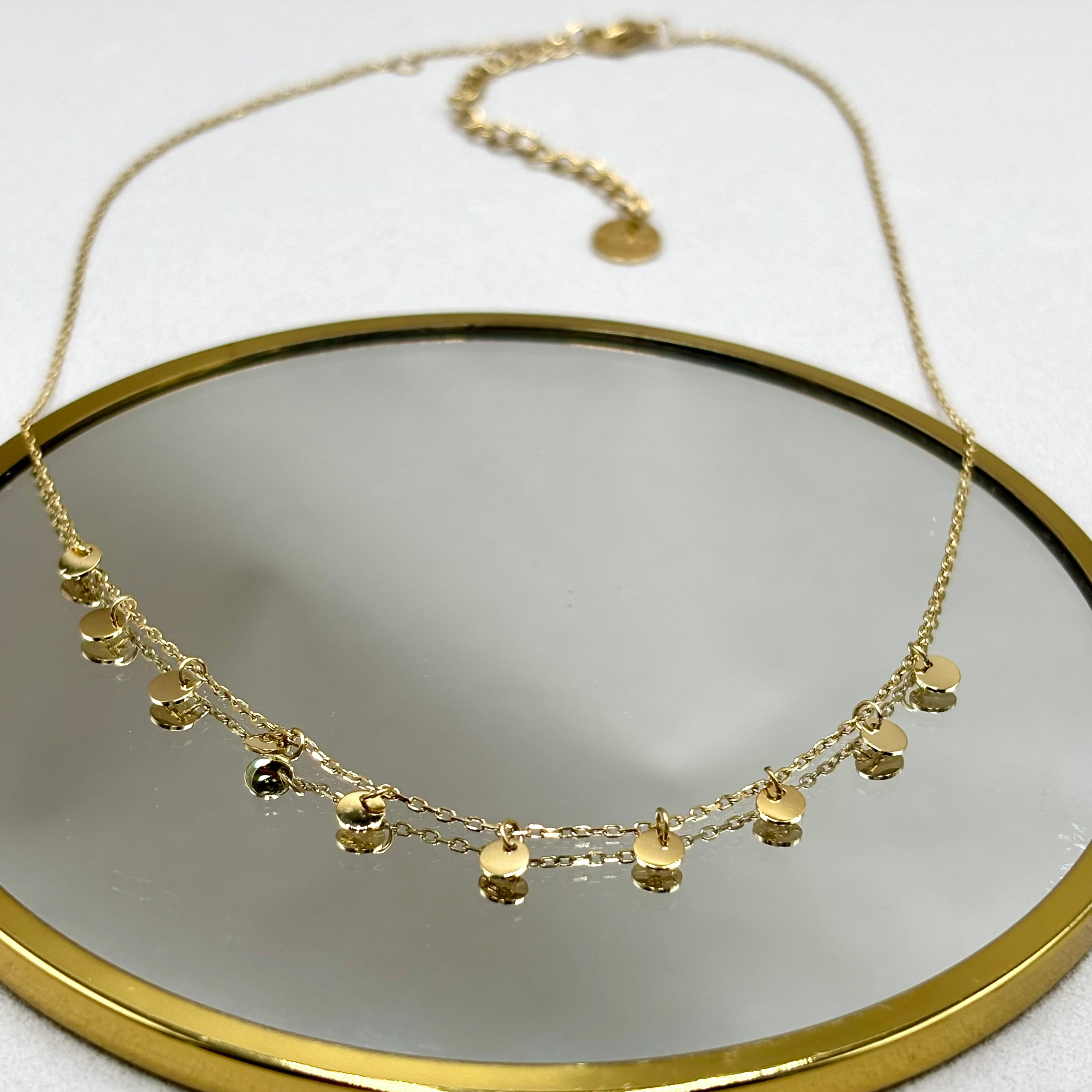 Collier ras de cou pastilles en acier inoxydable doré à l'or fin Djanet Bijoux présenté sur miroir